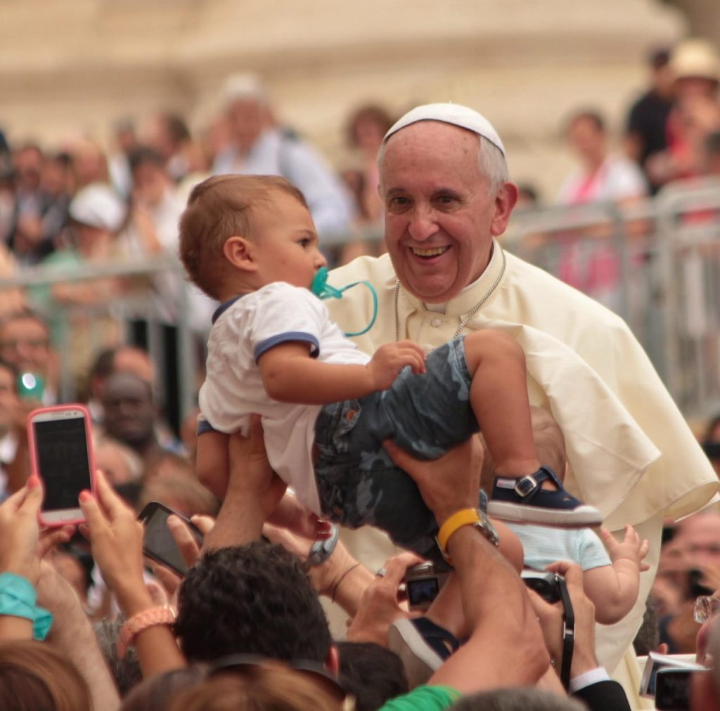 Le Pape François tenant un jeune enfant dans ses bras lors d'une audience publique.