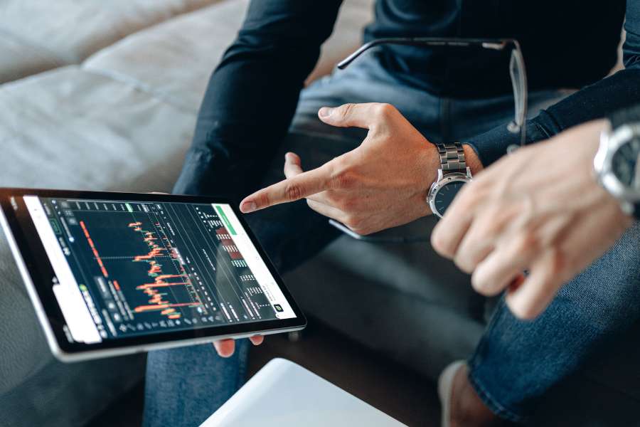 Professionnel analysant des graphiques de performance de marketing digital sur une tablette, portant une montre élégante