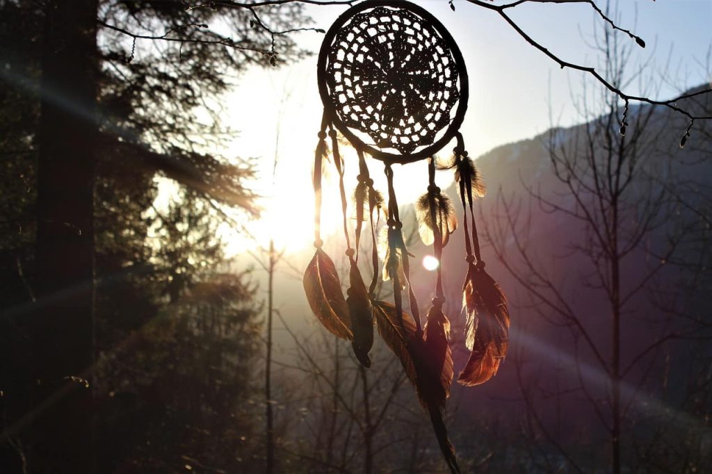 Attrape-rêves magique en silhouette suspendu dans une forêt au lever du soleil