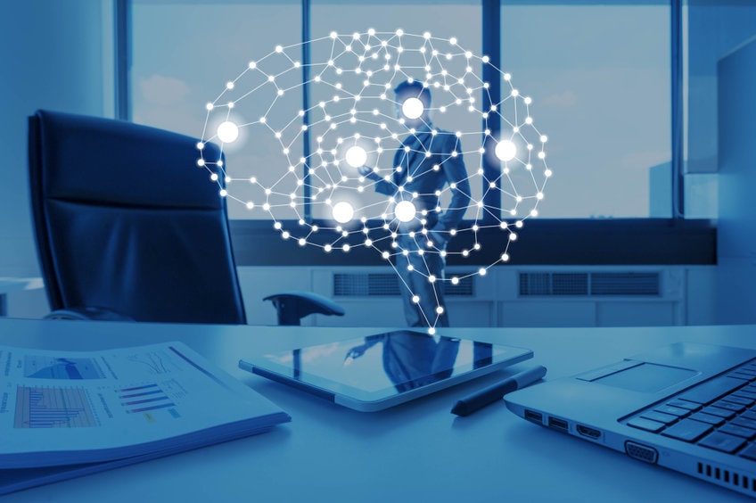 Hologramme de cerveau connecté au-dessus d'une tablette sur bureau professionnel représentant une solution de business intelligence