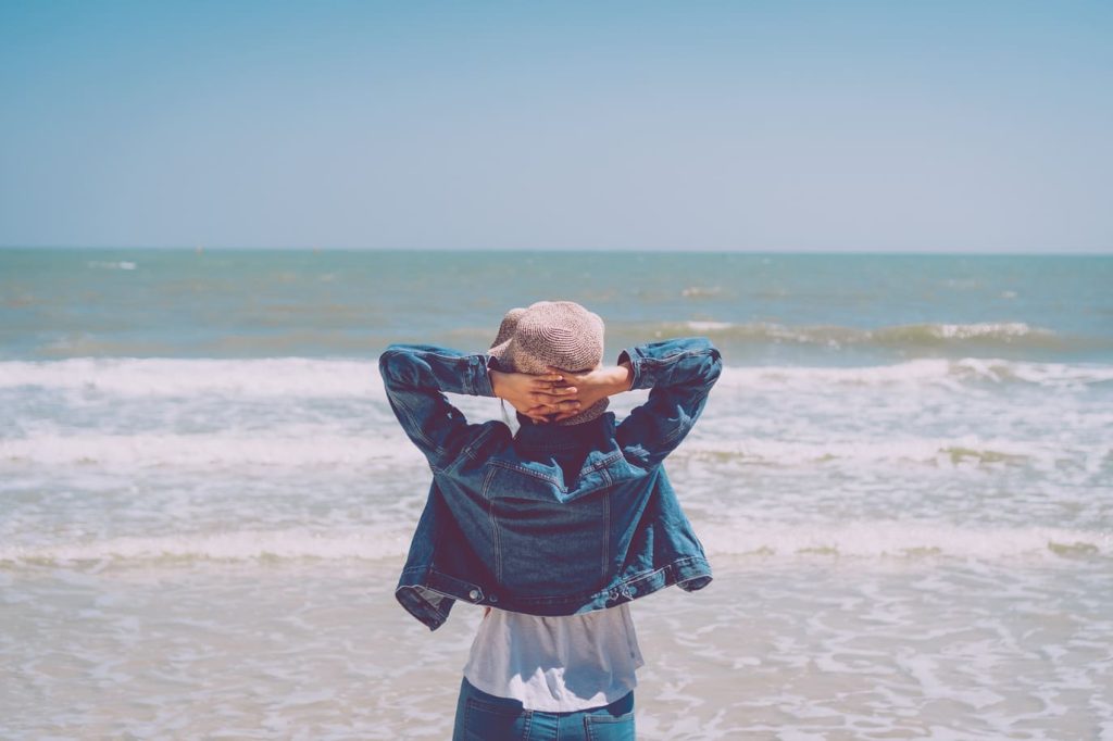 Femme contemplant l'océan depuis la plage, expérimentant le lien entre forme, rythme et perception des vagues