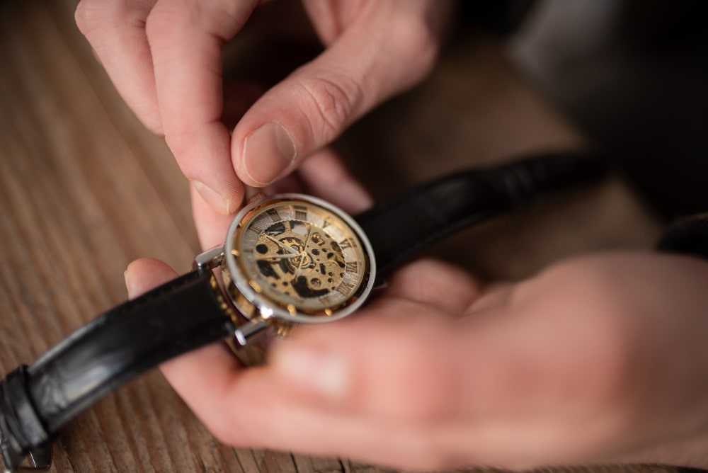 Une montre-bracelet classique et élégante avec un bracelet en cuir, posée sur une surface sombre, évoquant l'horlogerie de qualité