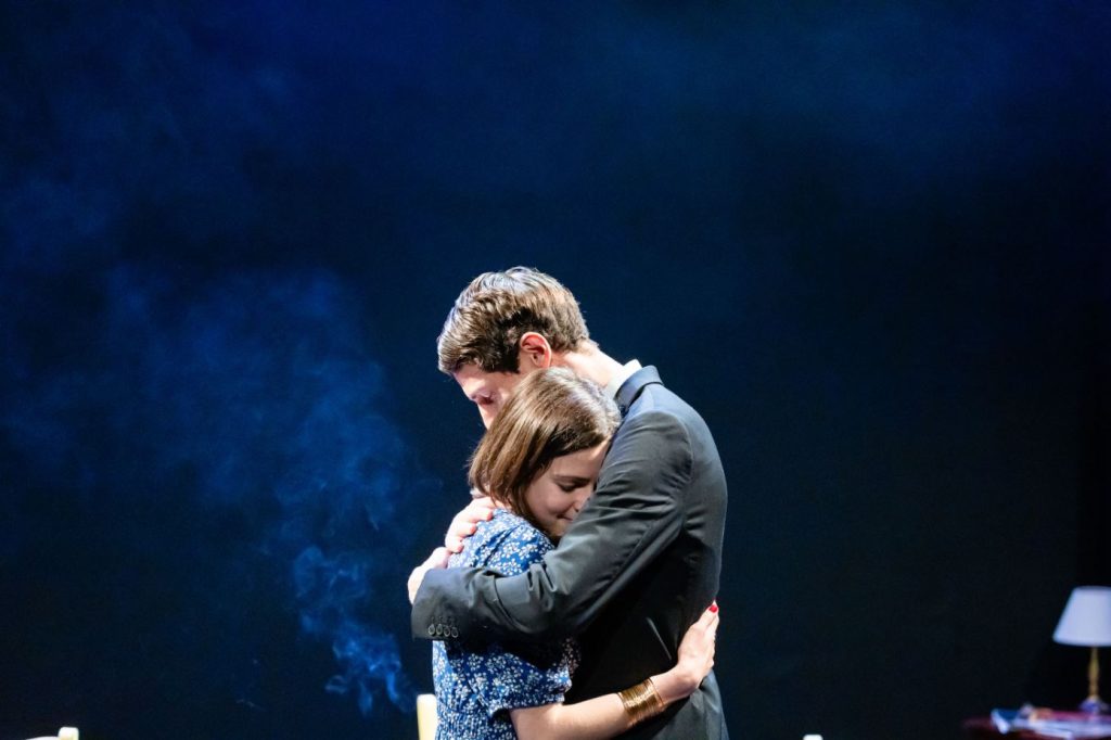 Un homme et une femme s'enlacent sur scène, une scène poignante de théâtre.