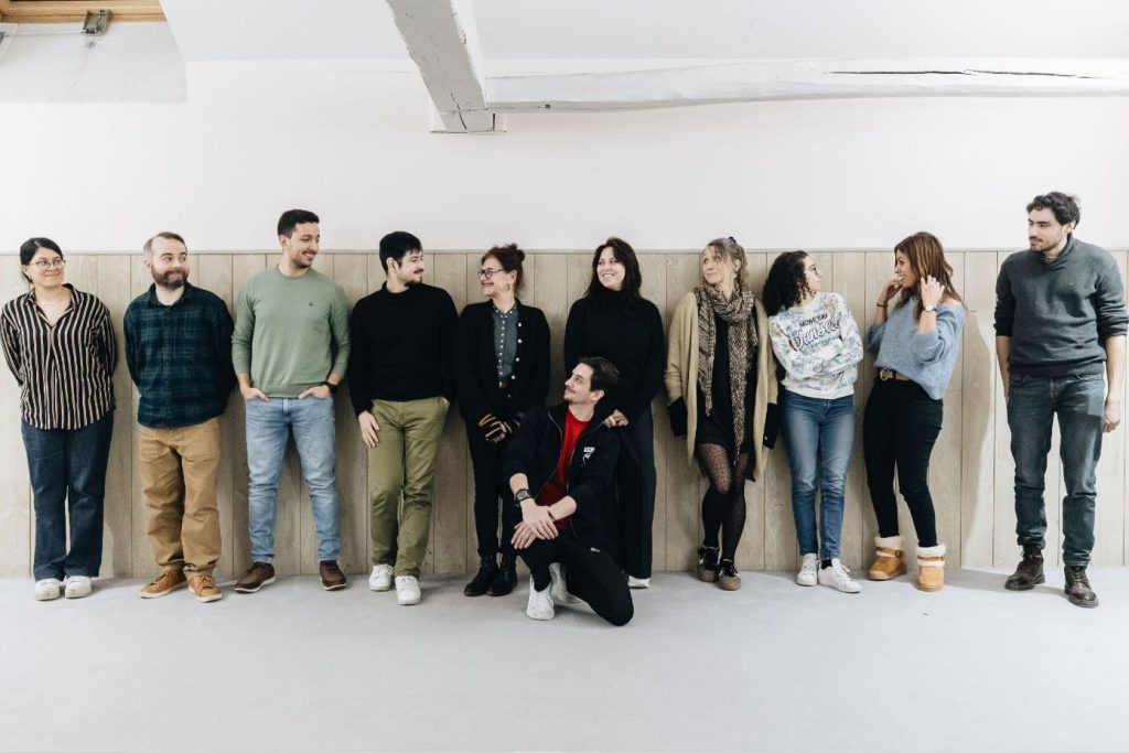 Un groupe de comédiens et de comédiennes du Théâtre, posant côte à côte dans une salle de répétition lumineuse.