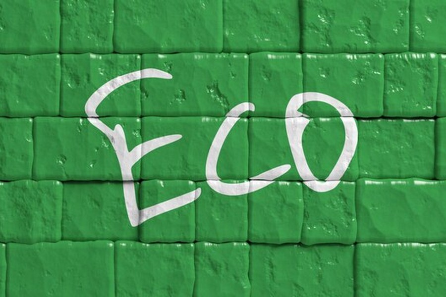 Un mur de briques vertes texturées affichant le mot ECO, illustrant le concept de l'Eco brick durable.