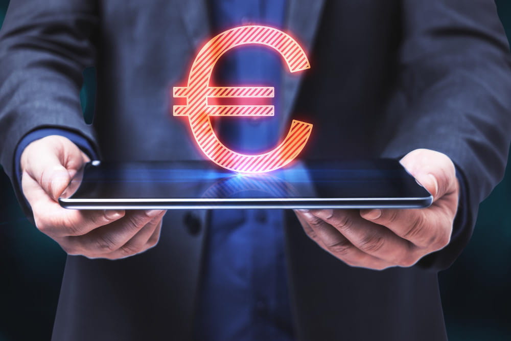 Un homme en costume tenant une tablette de laquelle émerge un symbole de l'Euro numérique en hologramme rouge