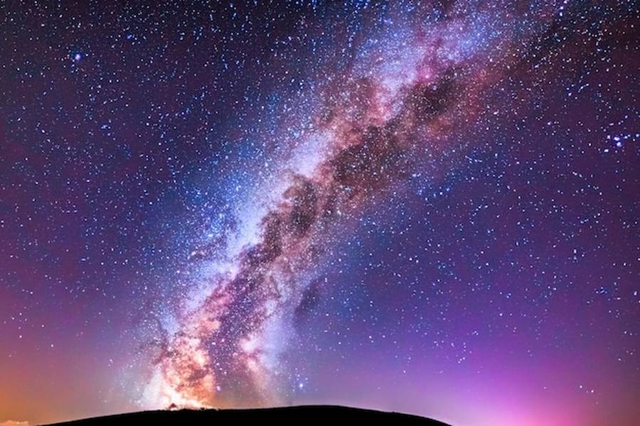 La voûte céleste révèle l'éclat de la Milky Way au-dessus d'un horizon sombre.