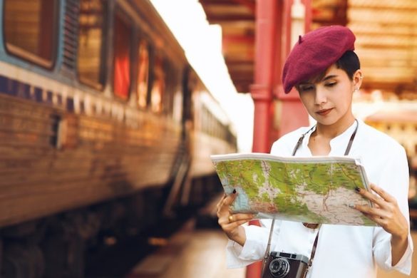 Une voyageuse passionnée consulte une carte sur un quai de gare, une étape clé de ce Guide complet pour voyager en train en Ouzbékistan : itinéraire sur la Route de la Soie.