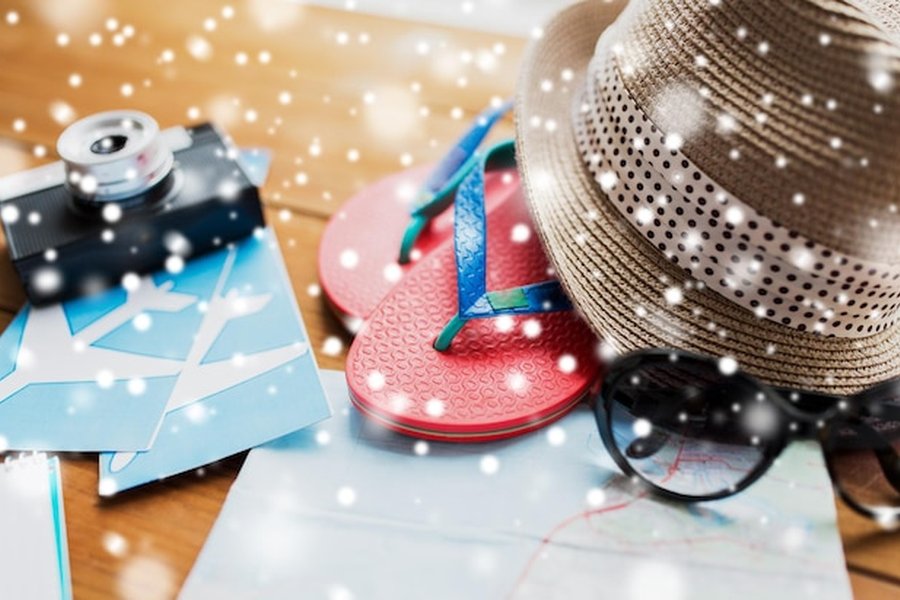 Accessoires de voyage estivaux comme un chapeau et des tongs recouverts de neige, illustrant le Cool-cationing : le guide des destinations pour fuir les canicules estivales.