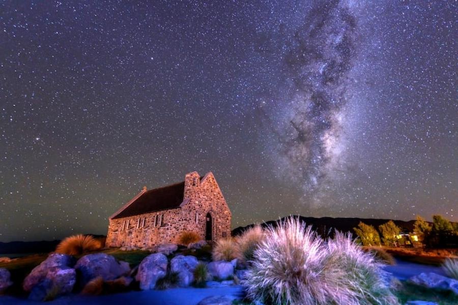 Une chapelle en pierre sous un ciel étoilé éclatant, représentant les meilleurs spots d'astrotourisme en Europe pour observer la Voie Lactée sans pollution lumineuse.