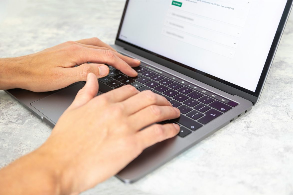 Gros plan des mains d’un professionnel utilisant un ordinateur portable pour illustrer l'intégration de l'IA journalisme dans la rédaction de contenus modernes.