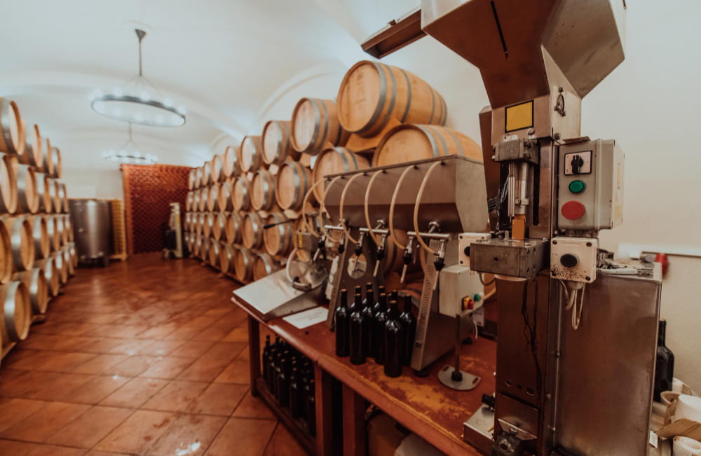 Intérieur de cave à vin traditionnelle avec tonneaux en bois et équipement de pressoir viticole et de mise en bouteille