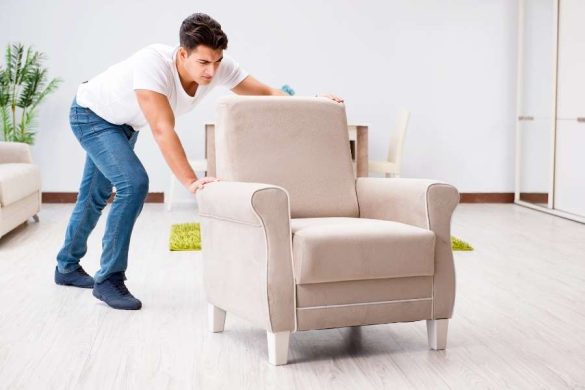 Un homme déplaçant un fauteuil classique pour réorganiser son intérieur et changer le style de mobilier.